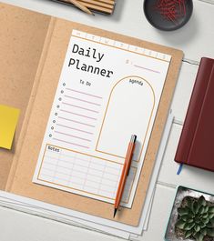 an open daily planner sitting on top of a desk next to some pens and pencils