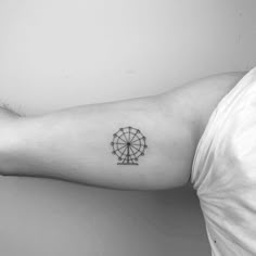 a black and white photo of a person's arm with a ferris wheel tattoo on it