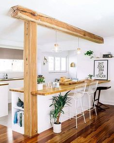 an open concept kitchen and dining area with wood flooring, white walls and wooden beams