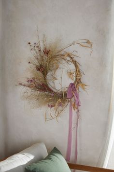 a dried wreath hangs on the wall next to a bed with pillows and throw pillows