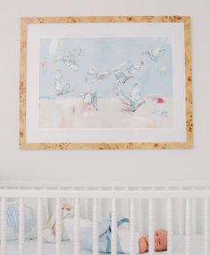 a white crib with a painting hanging above it