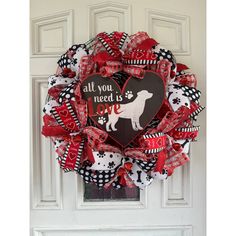 a red and black wreath with a dog's heart on it that says, all you need is love