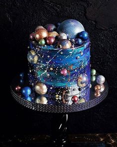 a cake decorated with planets and stars on a stand in front of a black background