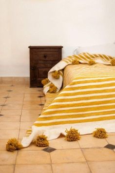 a yellow and white striped bedspread with pom poms