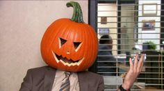 a man in a suit and tie with a pumpkin on his head