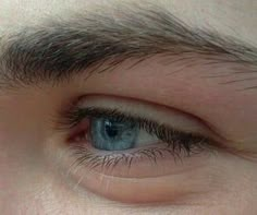 a close up view of the eye of a man with blue eyes and black hair