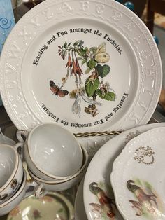 there are many plates and cups on the table, including one with a bird design