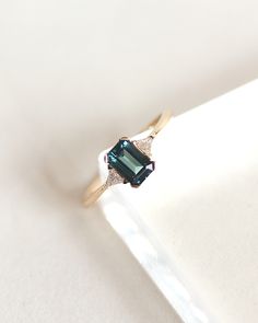 a ring with a blue stone in it on a white surface