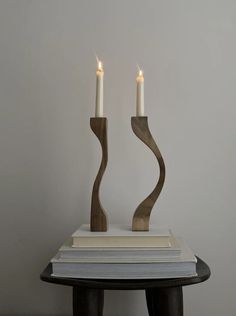 two candles sitting on top of a book next to each other in front of a white wall