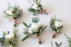 wedding boutions with white flowers and greenery laid out on a table top for the bride's bouquets