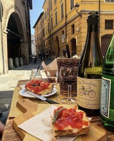 there is a bottle of wine and two plates with food on the table next to it