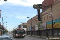 a bus driving down a street next to tall buildings with signs on the side of it