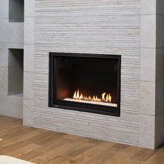 a fire place in the middle of a living room with wood flooring and white brick walls