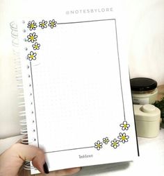 someone holding up a notebook with flowers on it