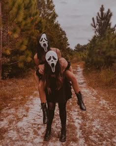 two people with masks on walking down a dirt road