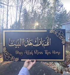 a person holding up a sign in front of some trees