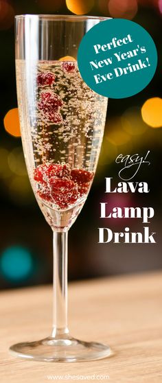 a glass filled with liquid sitting on top of a wooden table next to a christmas tree