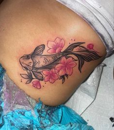 a woman's stomach with a koi fish and flowers tattoo on her side