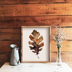 an image of a leaf in a frame next to some vases on a table