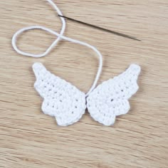 a pair of white crocheted angel wings sitting on top of a wooden table