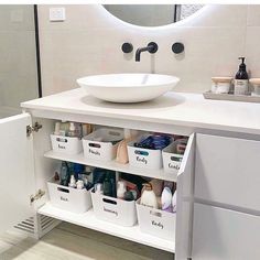 a white sink sitting under a bathroom mirror next to a counter top with containers on it