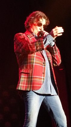 a man standing on top of a stage with his hands in his pockets as he sings