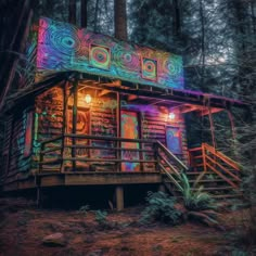 a cabin in the woods with colorful lights on it's roof and stairs leading up to