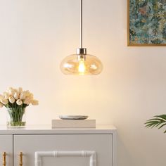 a table with flowers and a vase on it next to a wall mounted light fixture