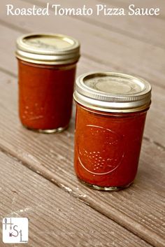 two jars filled with tomato sauce sitting on top of a wooden table