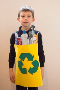 a young boy is dressed up as a recyclist and holding a yellow bag