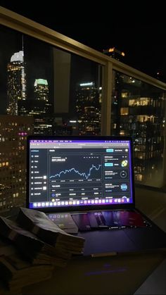 an open laptop computer sitting on top of a desk in front of a large window