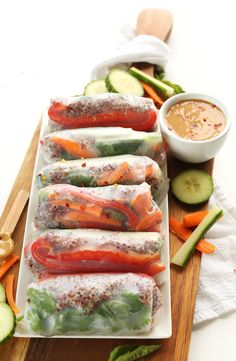 vegetable spring rolls with dipping sauce and cucumbers on the side, ready to be eaten