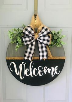 a welcome sign hanging on the front door with a bow around it's neck