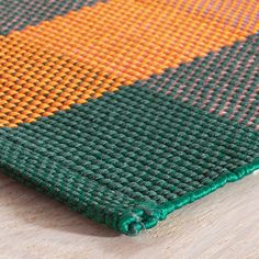 an orange and green rug on top of a wooden table with a wood floor in the background