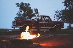 a red pick up truck parked next to a fire pit in the middle of a field