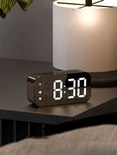 an alarm clock sitting on top of a table next to a lamp