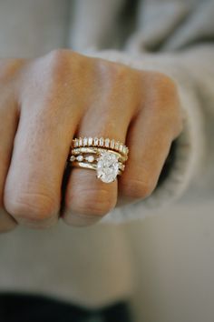 a woman's hand with two gold rings and a diamond ring on her finger