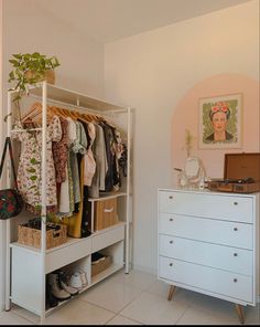 a closet with clothes and shoes hanging on the rack, next to a white dresser