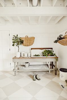 a white bench sitting in the middle of a room next to potted plants and other items