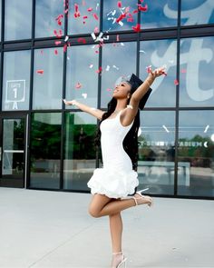 a woman in a white dress and black hat throwing confetti into the air