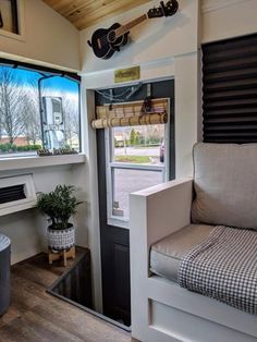 a living room with a couch and guitar hanging on the wall next to a window