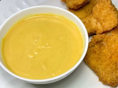 a white plate topped with fried food next to a bowl of soup and tater tots