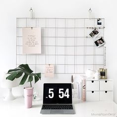 a laptop computer sitting on top of a white desk next to a potted plant