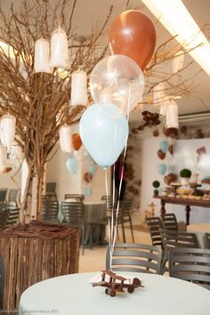 several balloons are floating in the air over a table with chairs and tables set up for an event