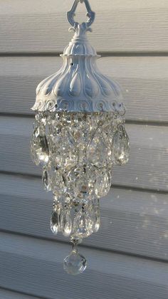 a glass chandelier hanging from the side of a house in front of a window