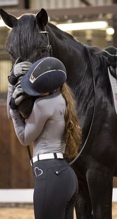 a woman standing next to a black horse