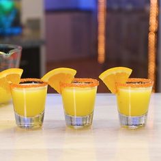 three shot glasses filled with orange juice and garnish