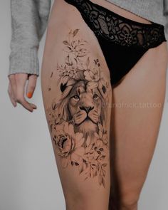 a woman's thigh with a lion and flowers tattoo on the side of her leg