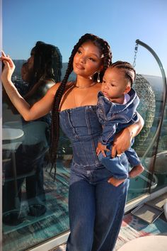 a woman holding a baby in her arms on the top of a building with other people