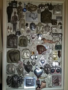 an assortment of metal items on display in a white frame with magnets attached to it